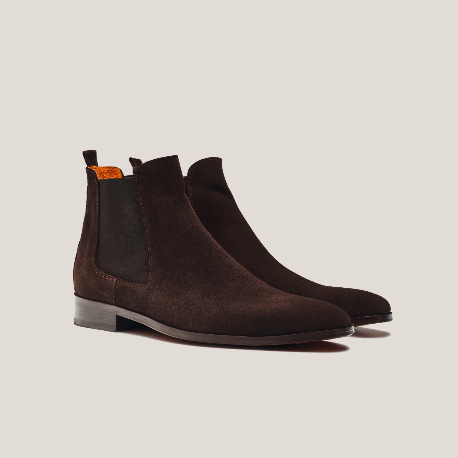 Pair of brown suede Chelsea boots on a light gray background