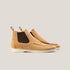 A pair of light beige suede Chelsea boots with a white sole and dark brown detailing.