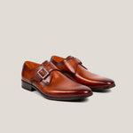A pair of cognac brown patina leather single monk shoes with a square buckle.